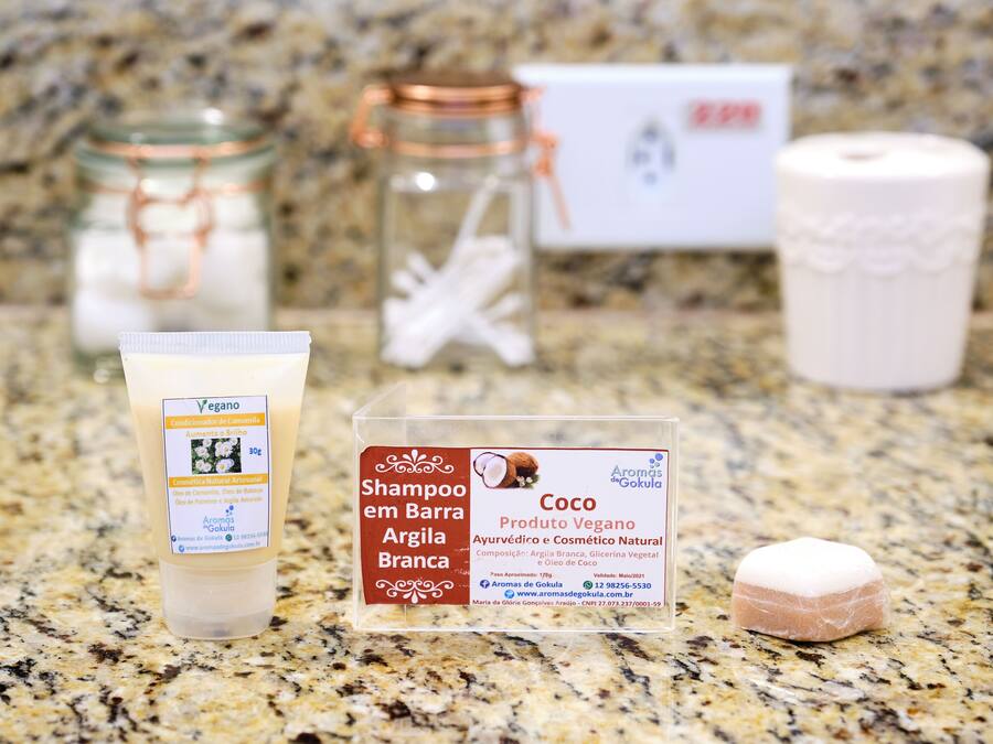 A product display with a shampoo bottle, a jar, a candle, and a box on a granite countertop.