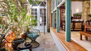 A cozy patio with stone flooring, a hanging chair, and a wooden bench. - A Casa de Paulo Autran (Paraty)