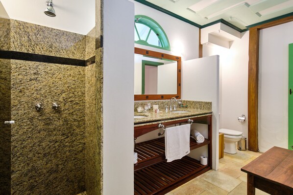 A bathroom with a granite countertop sink, a mirror, a toilet, and a wooden vanity. - A Casa de Paulo Autran (Paraty)