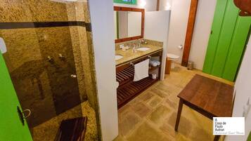 Un baño con tocador de granito, ducha, inodoro y puerta verde.