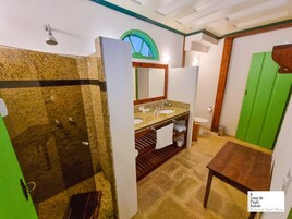 Un baño con tocador de granito, ducha, inodoro y puerta verde.