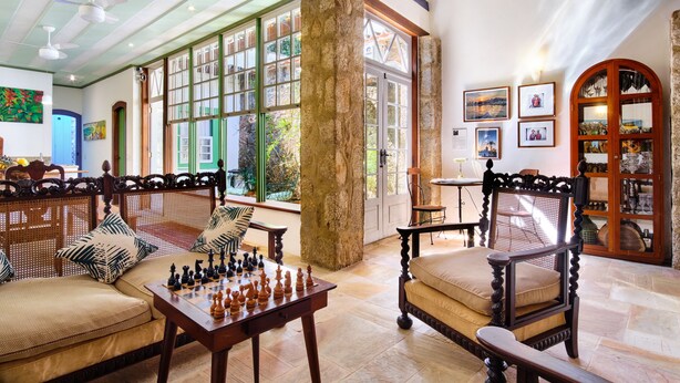 A spacious room with a large window, a chessboard, and a wooden cabinet with glass doors. - A Casa de Paulo Autran (Paraty)