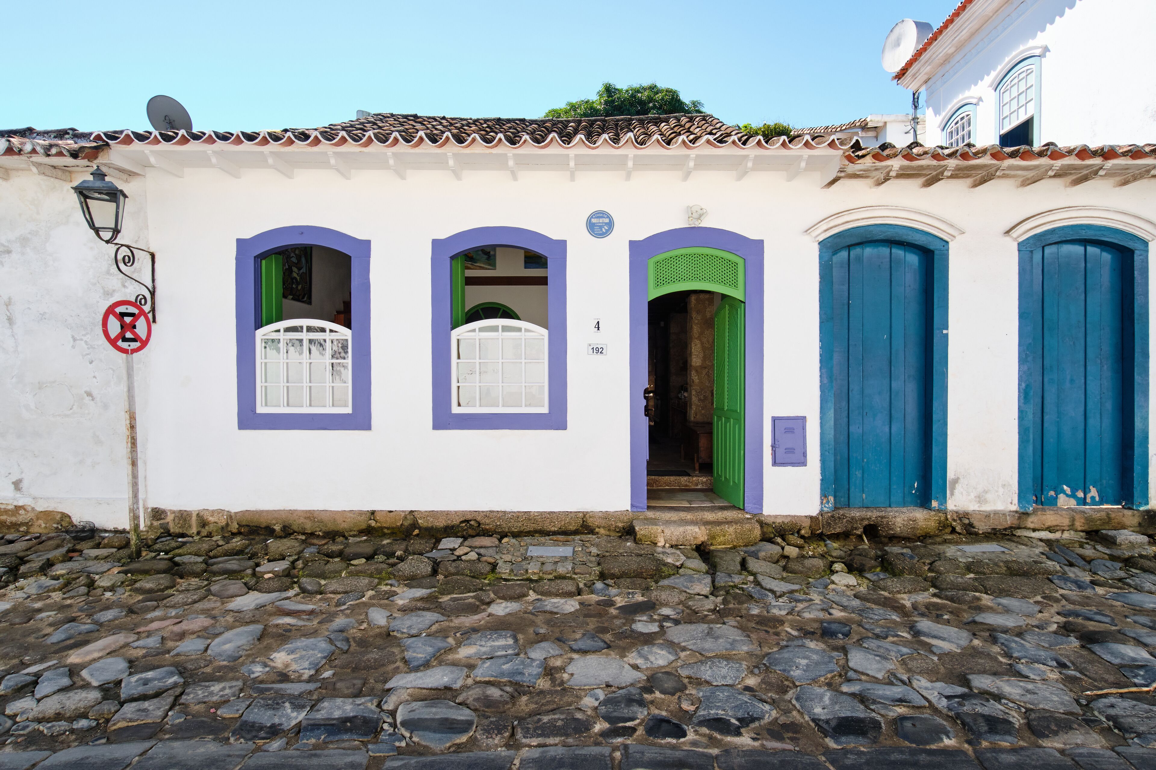 Um edifício com três janelas em arco, uma porta verde e duas portas azuis.