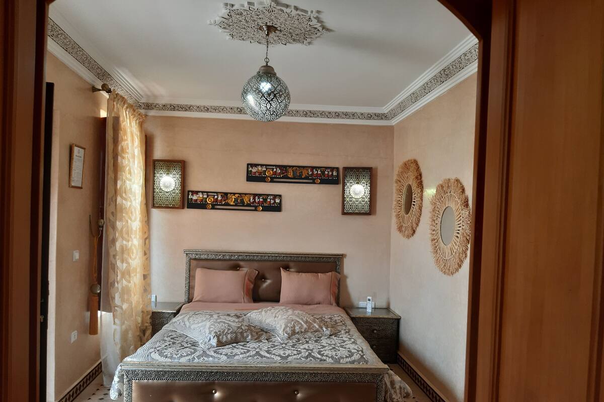 Ein Schlafzimmer mit einem großen Bett, Wanddekoration und einer Pendelleuchte.