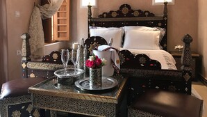 A traditional room with a bed, a table with decorative items, and a window with a view. - Riad Miral (Marrakech)