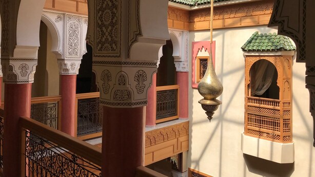An interior with arches, columns, and a hanging lamp. - Riad Miral (Marrakech)