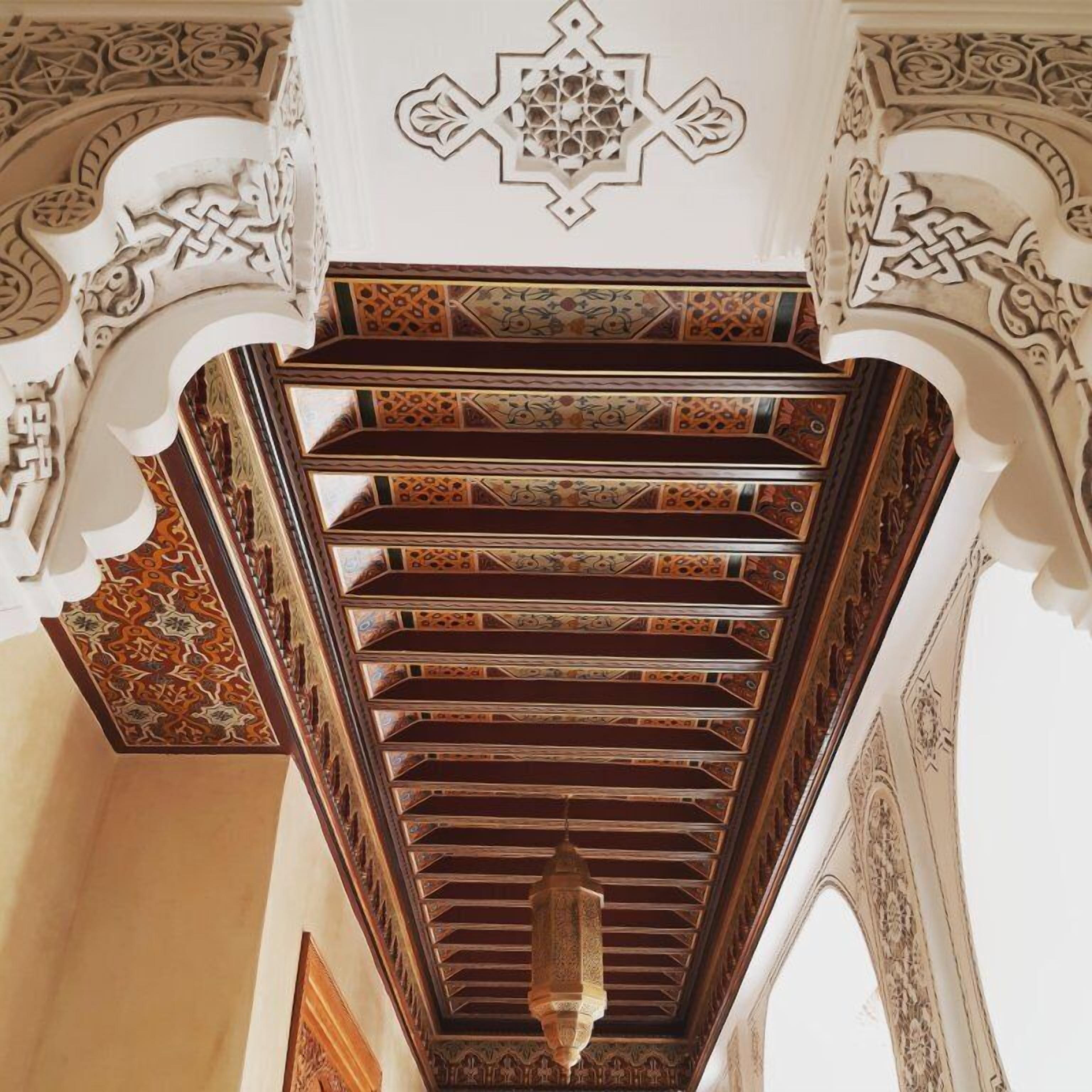 A spiral staircase with ornate carvings and a geometric pattern on the walls.