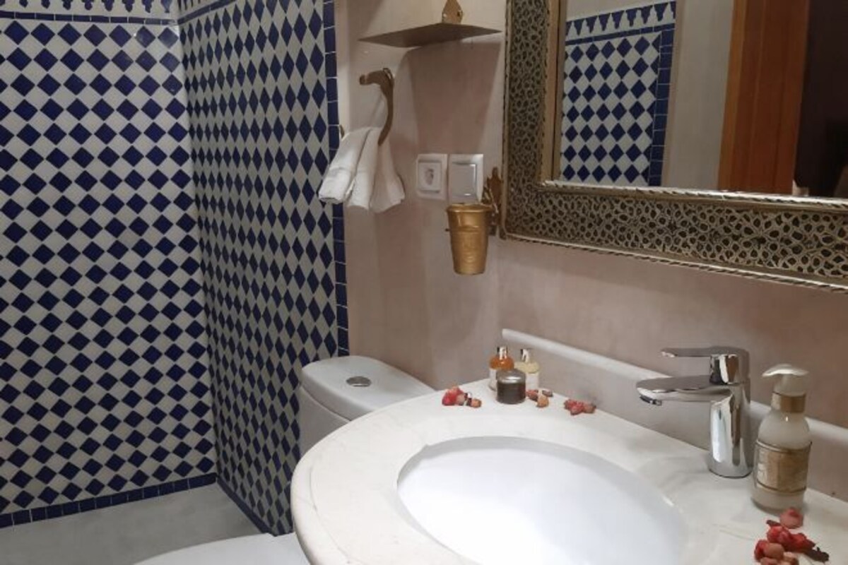 A bathroom with a white sink, a mirror, and a toilet.