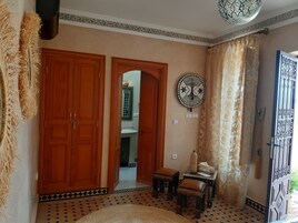 Una stanza con pavimento decorato, porte in legno, una piastrella decorativa a parete e un piccolo tavolo con una sedia.