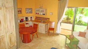 Una cocina compacta con zona de comedor, una mesita y un sofá.
