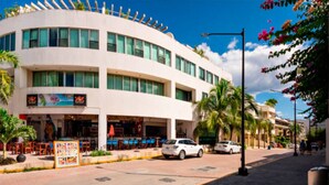 Un edificio de varios pisos con fachada curva, zona de estar al aire libre y palmeras.
