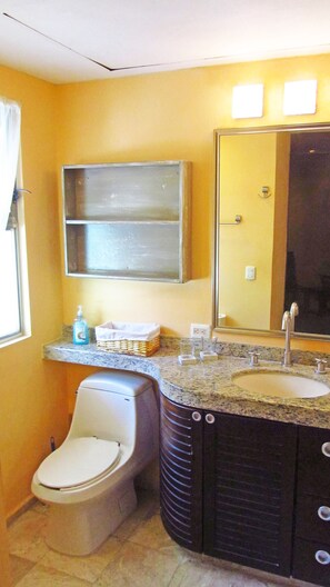 Une salle de bain avec des toilettes, un lavabo et un miroir.