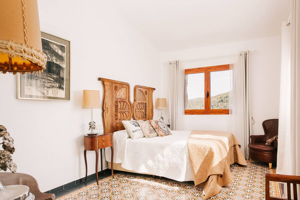 A bedroom with a bed, bedside tables, a chair, and a window with curtains.