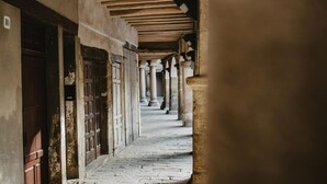 A corridor with stone flooring, wooden doors, and columns. - Vila Caelus Masia Boutique (Rubió)