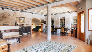 A spacious living area with a high ceiling, stone walls, and a large rug. - Vila Caelus Masia Boutique (Rubió)
