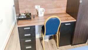 A compact room with a wooden desk, a chair, a small cabinet, and a kettle. - La Tavola Calda Hotel (Nuneaton)