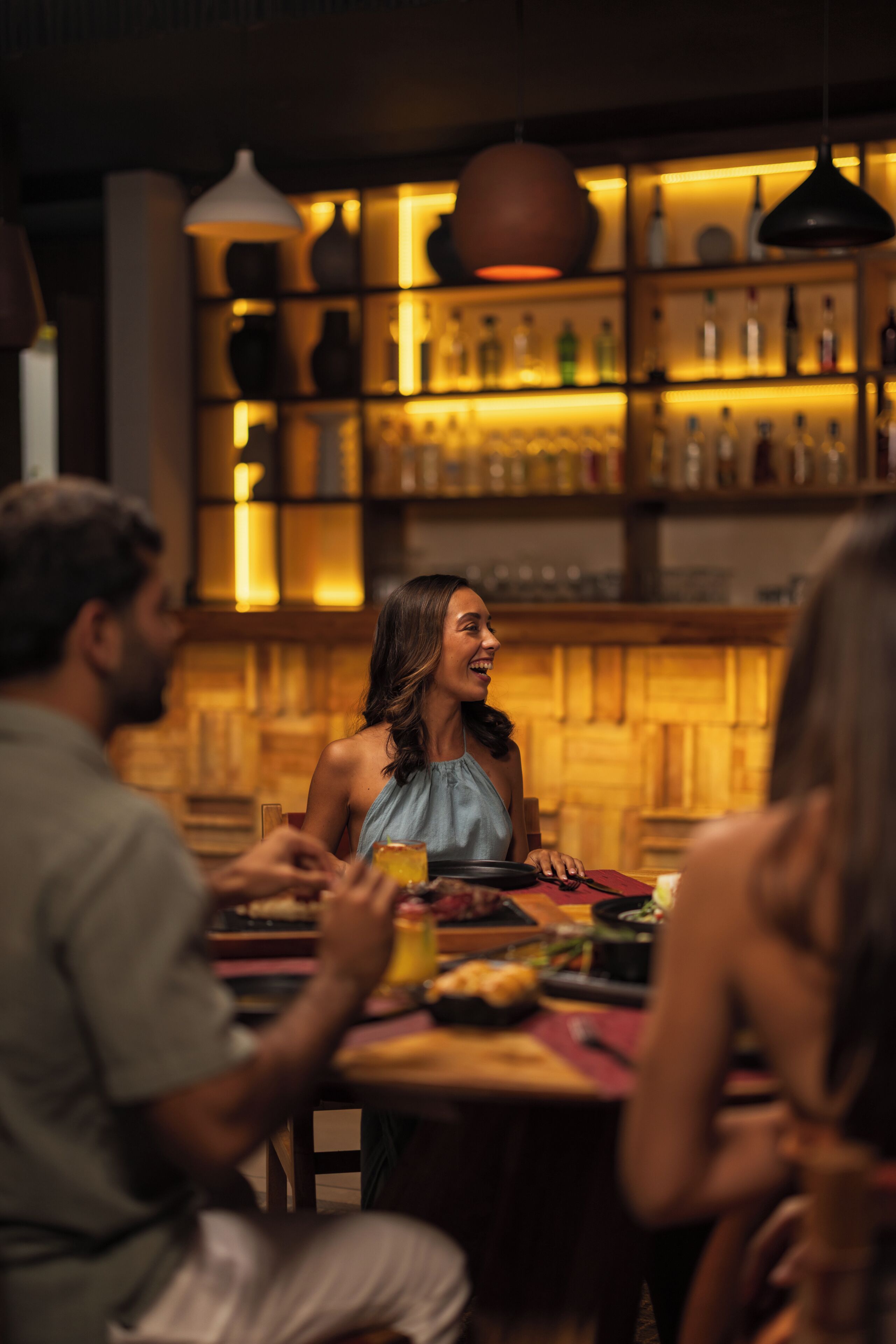 Un gruppo di persone che cena a un tavolo, con un bar sullo sfondo.