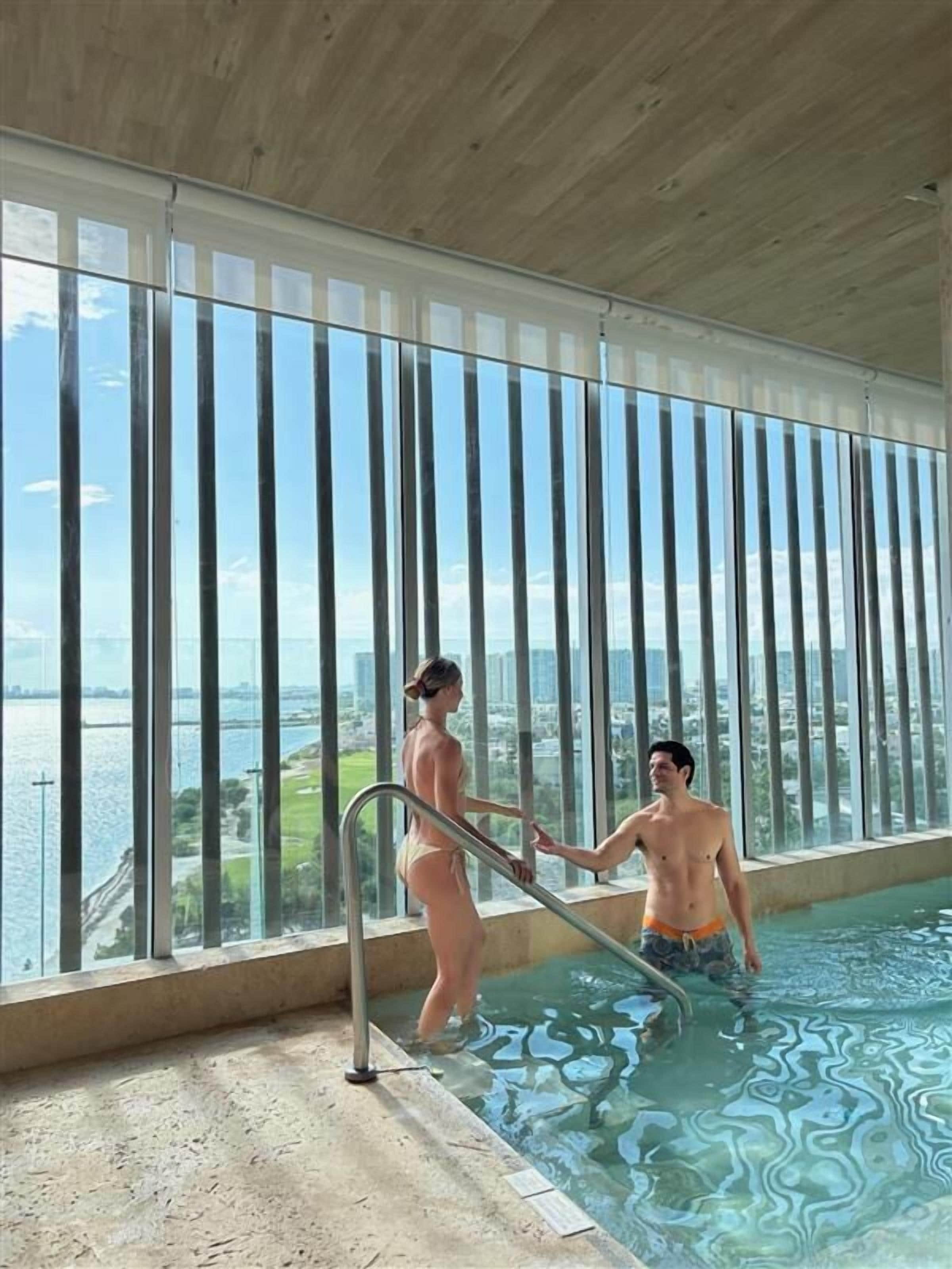 Zona de piscina con vistas a un paisaje urbano a través de amplios ventanales.