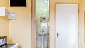 Un baño con lavamanos, espejo y televisor montado en la pared.