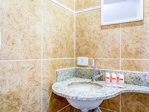 A bathroom with a sink, marble walls, and a mirror. - Hotel Macuco (São Paulo)
