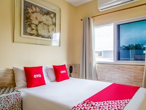 A hotel room with a bed, a telephone, a window with curtains, and a brick wall. - Hotel Macuco (São Paulo)