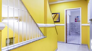 Un pasillo de colores llamativos con paredes amarillas, una escalera blanca y un suelo de baldosas.