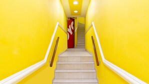 Una escalera con peldaños beige y barandillas blancas que conduce a una puerta roja con un logotipo blanco.