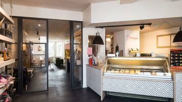 An ice cream shop with a display case, shelves with items, and a patterned counter.