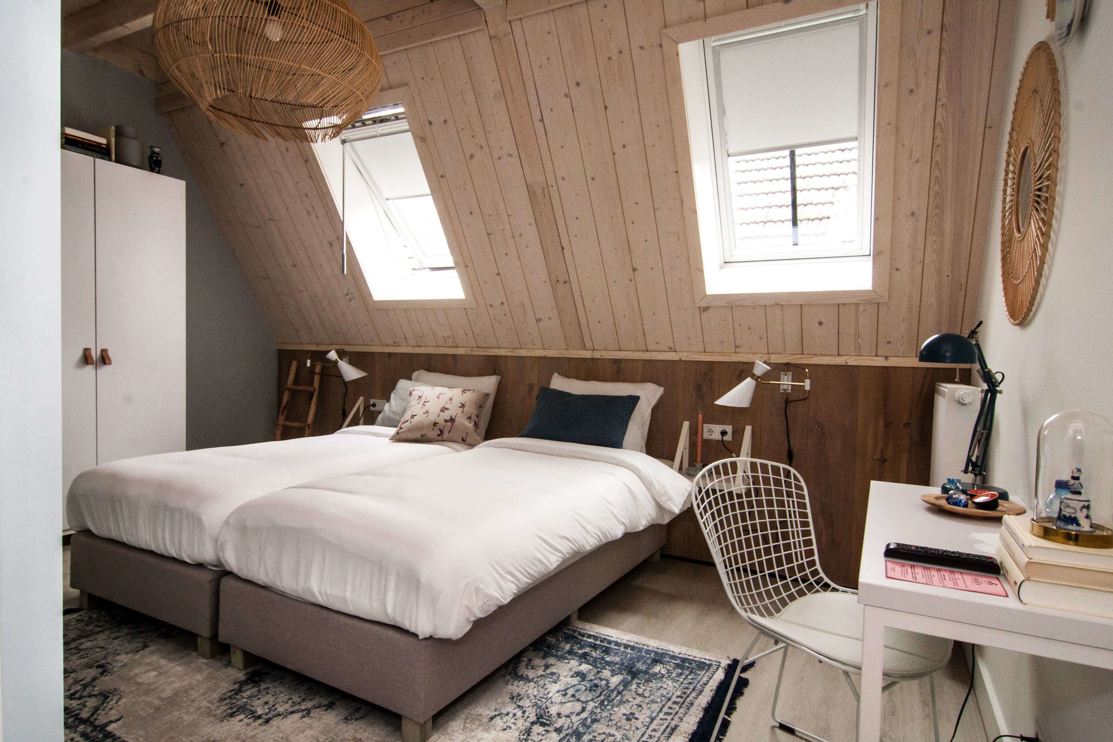 Un dormitorio con cama, escritorio, silla, ventana y ventilador de techo.
