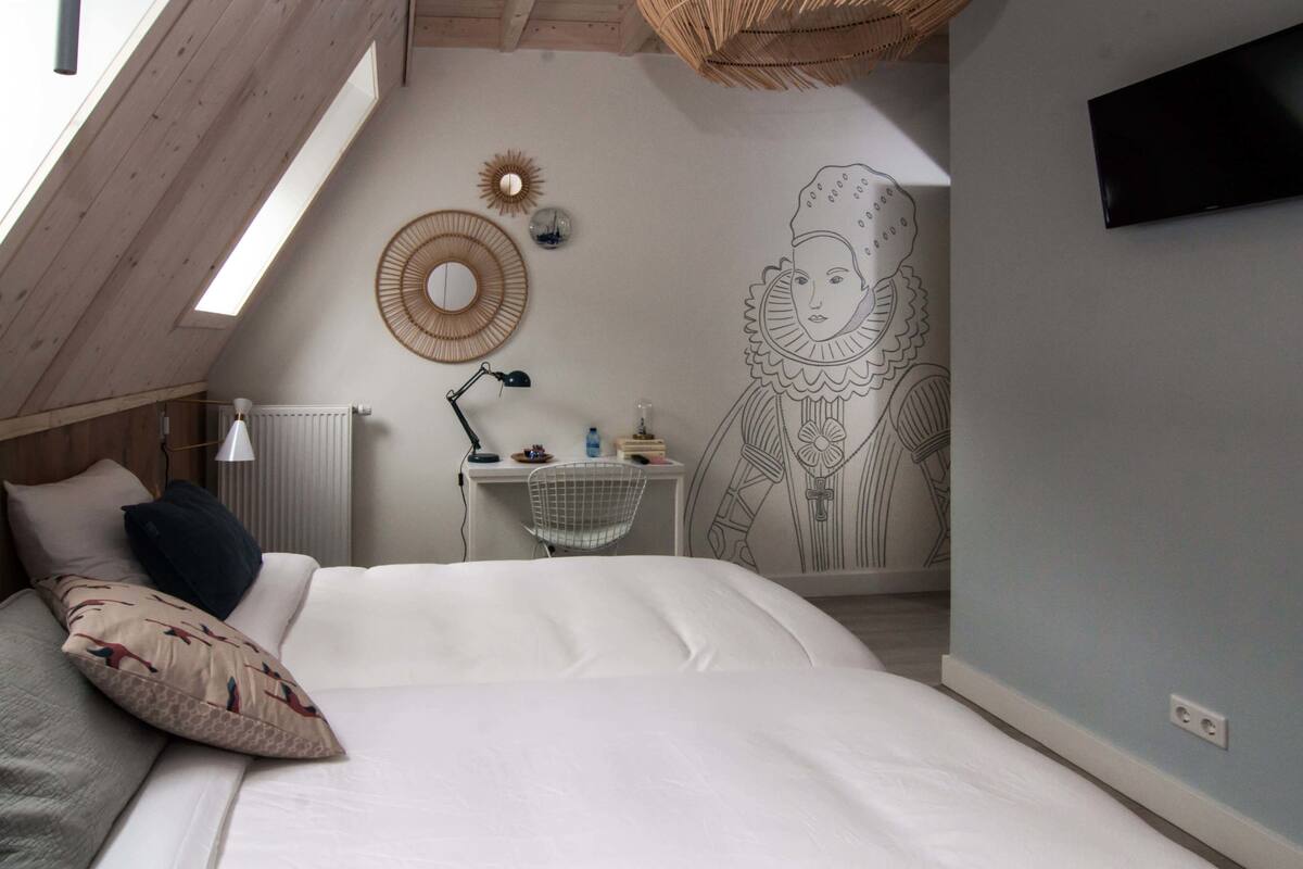 A bedroom with a bed, a desk, and a large wall mural.