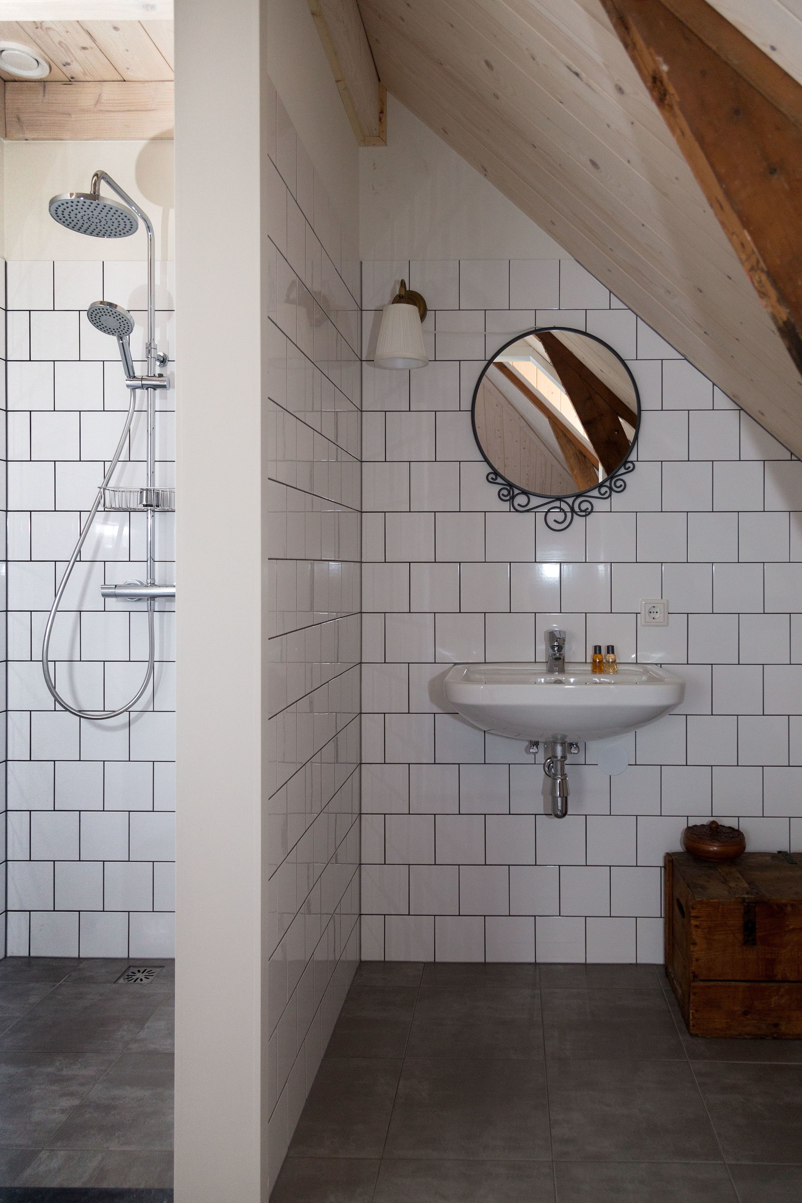 A bathroom with a shower, sink, and wooden beams.