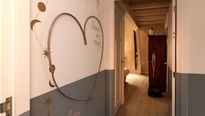 Um corredor com decoração na parede, incluindo um coração e motivos celestiais.