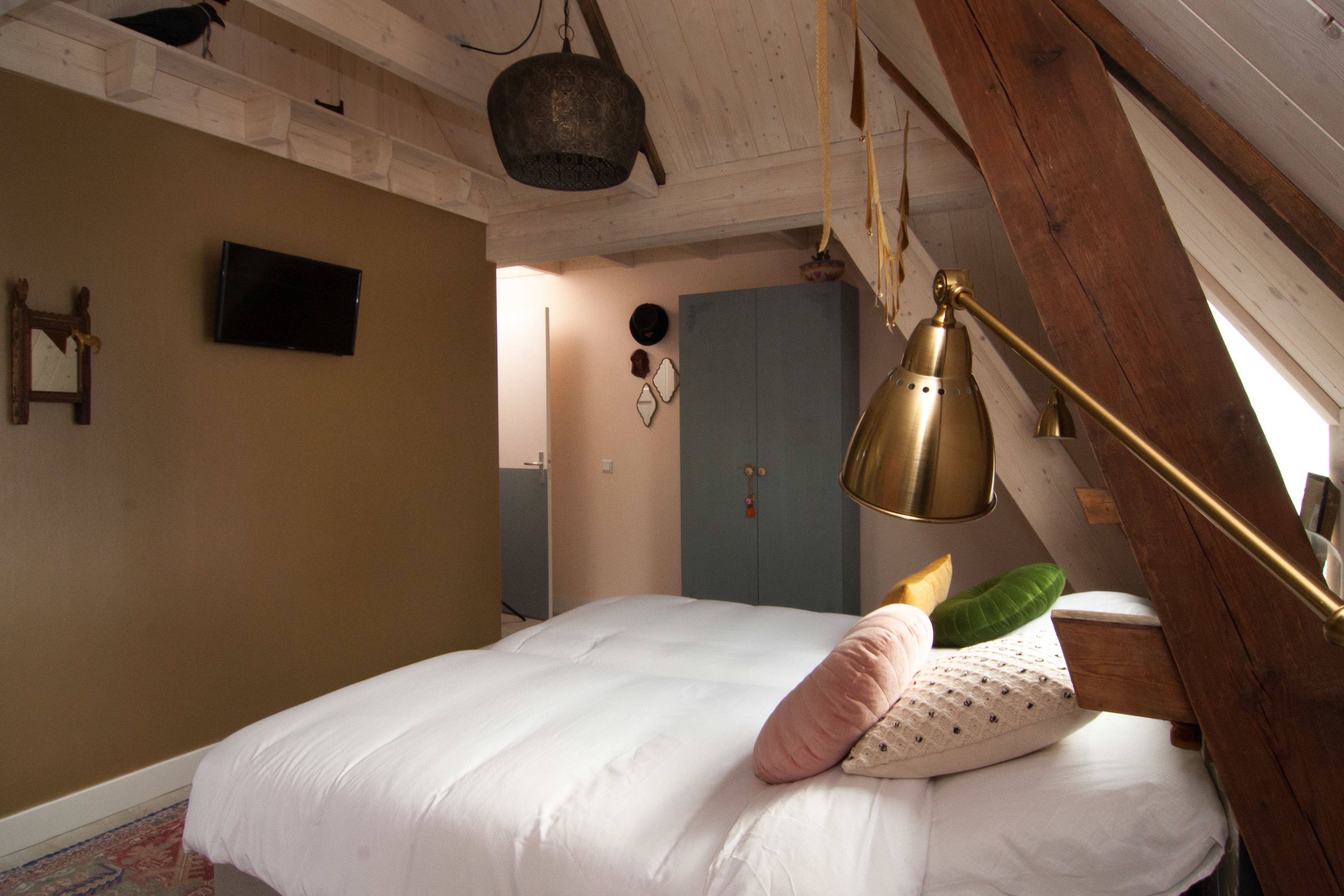 Un dormitorio con cama, techo de madera, televisor y una puerta.