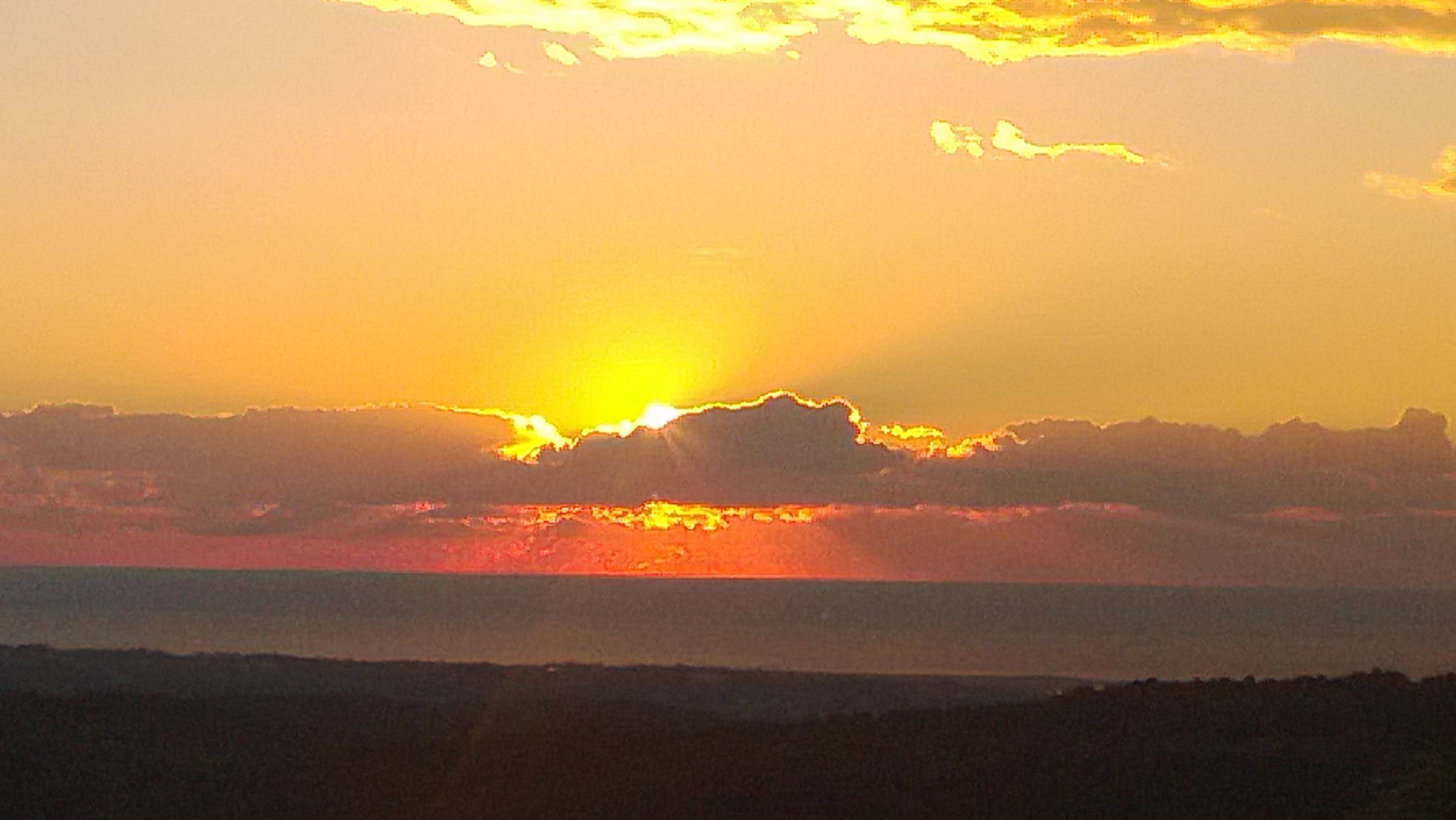 A sunset over a body of water with a distant mountain range.