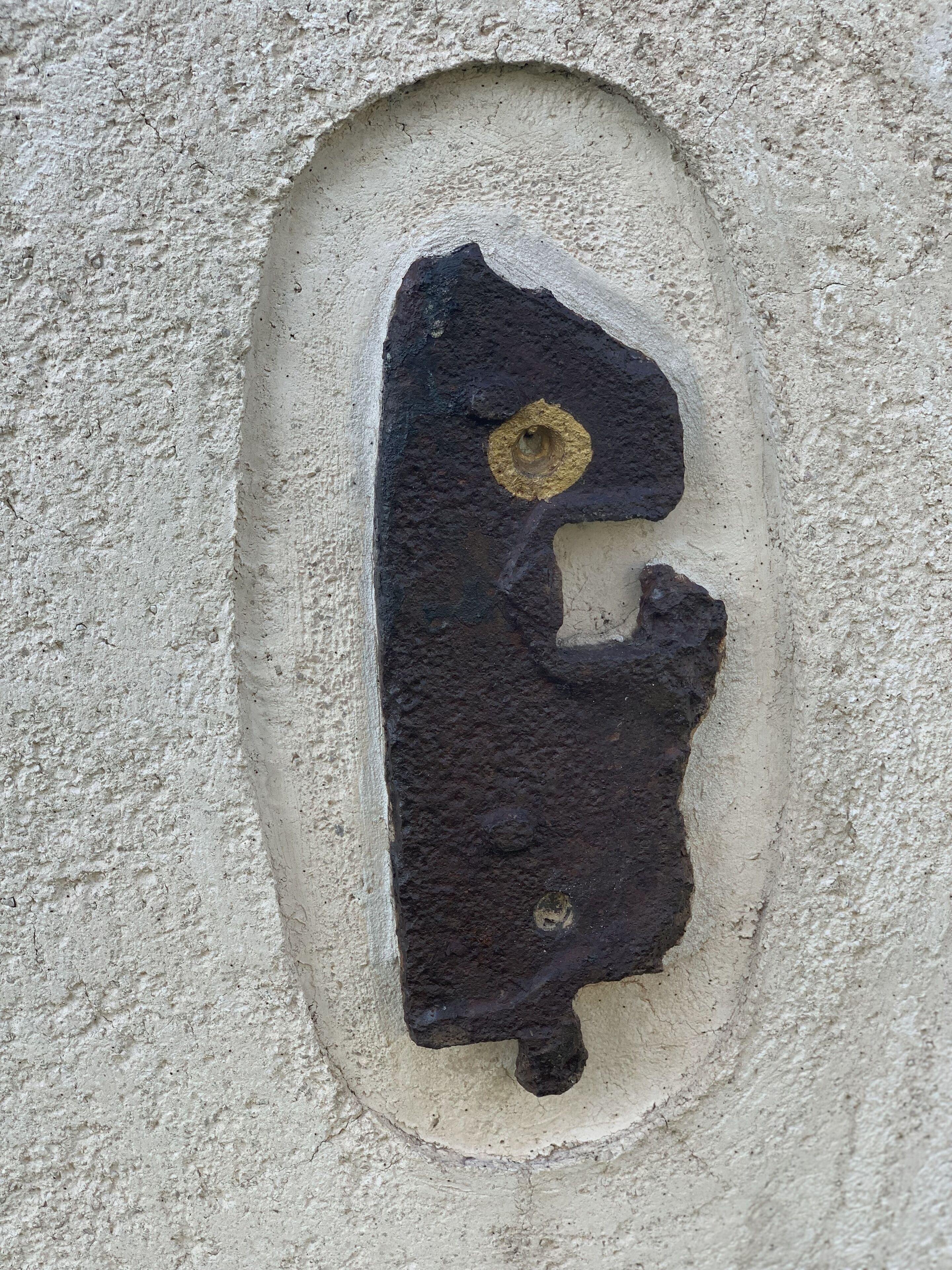 A black, oval-shaped object embedded in a textured wall.