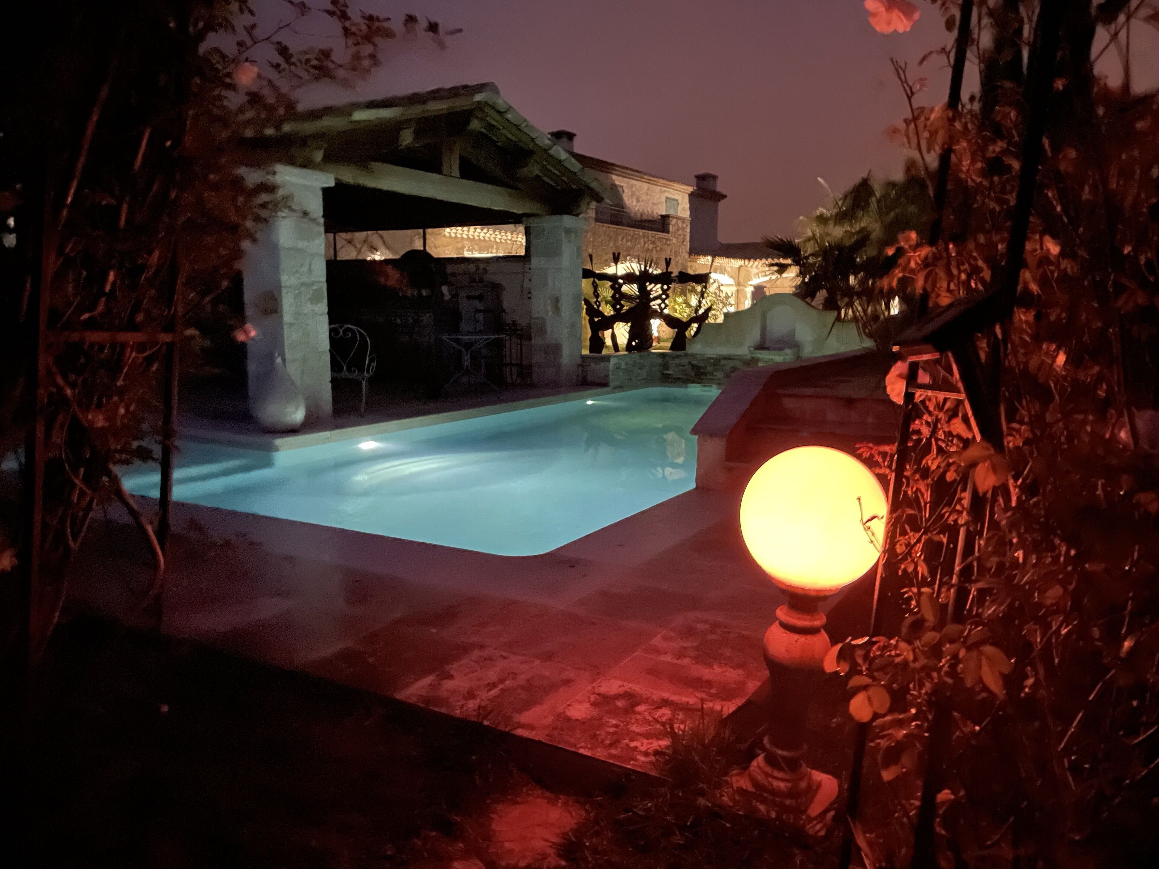 A swimming pool with a stone structure in the background, surrounded by vegetation.