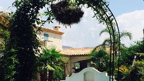 A pool area with a clear view of the water, surrounded by lush greenery and a stone structure. - Les 4 éléments (Tourrettes-sur-Loup)