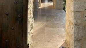 A corridor with stone walls and a wooden door, leading to a room with a view. - Les 4 éléments (Tourrettes-sur-Loup)