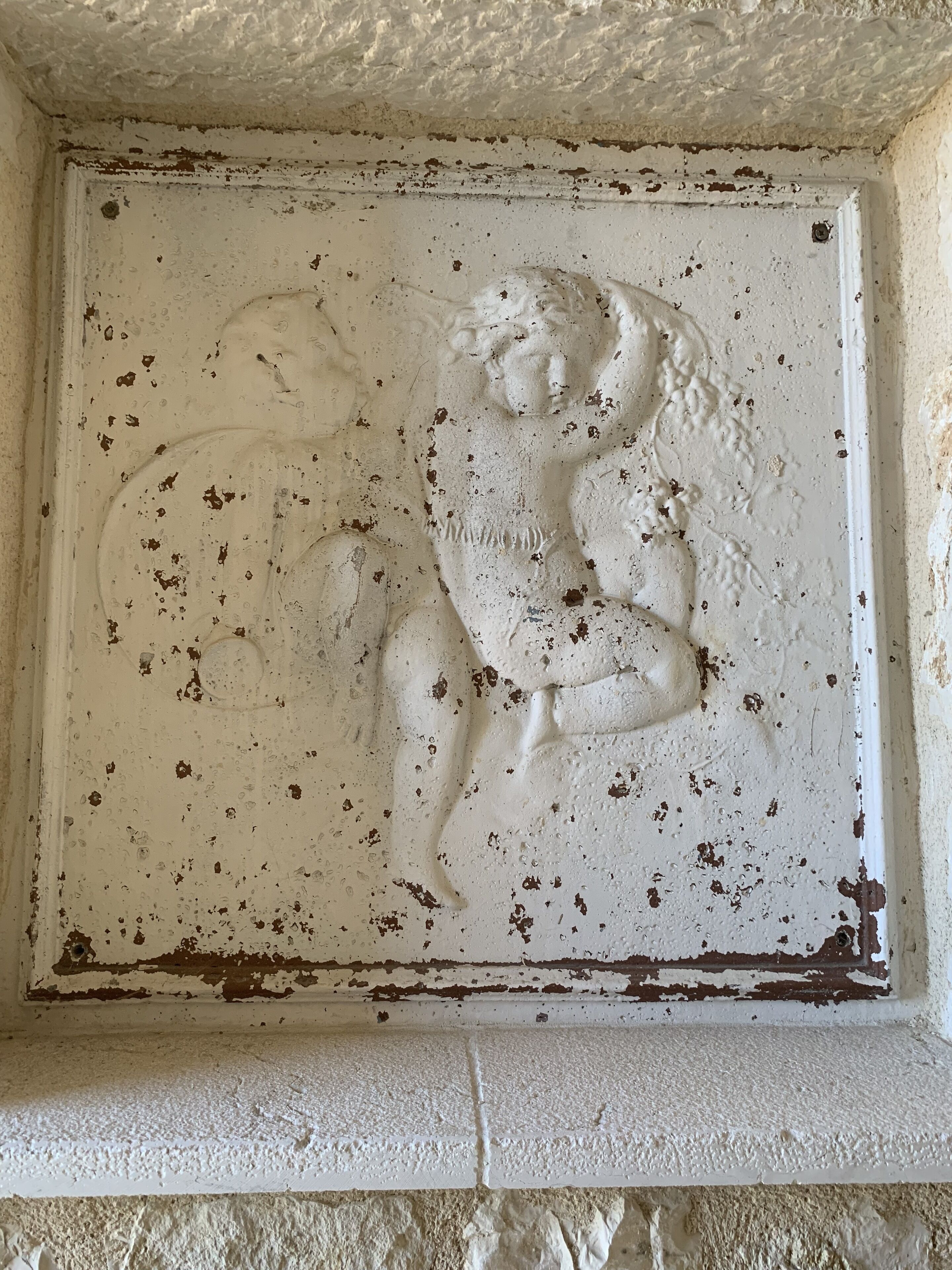 A weathered stone wall with a relief sculpture depicting a human figure.