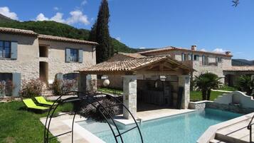 Een buitenzwembad, een infinitypool en ligstoelen