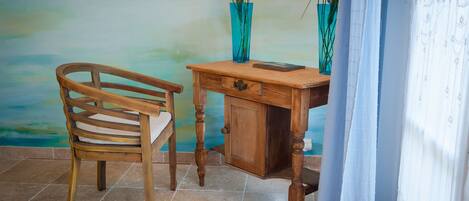 A wooden desk with a drawer, a chair, and two vases with flowers.