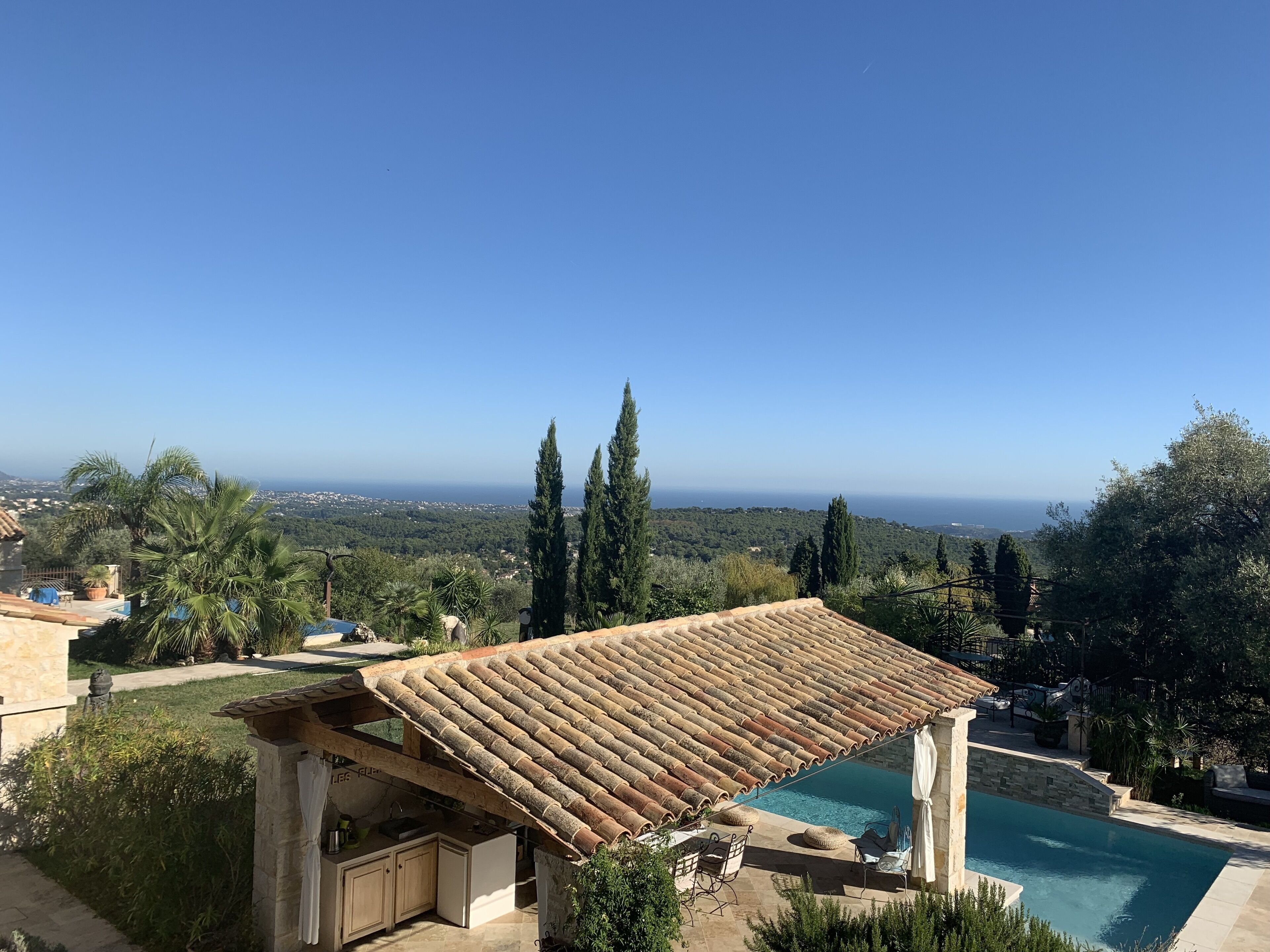 A villa with a swimming pool, stone architecture, and a view of the sea.