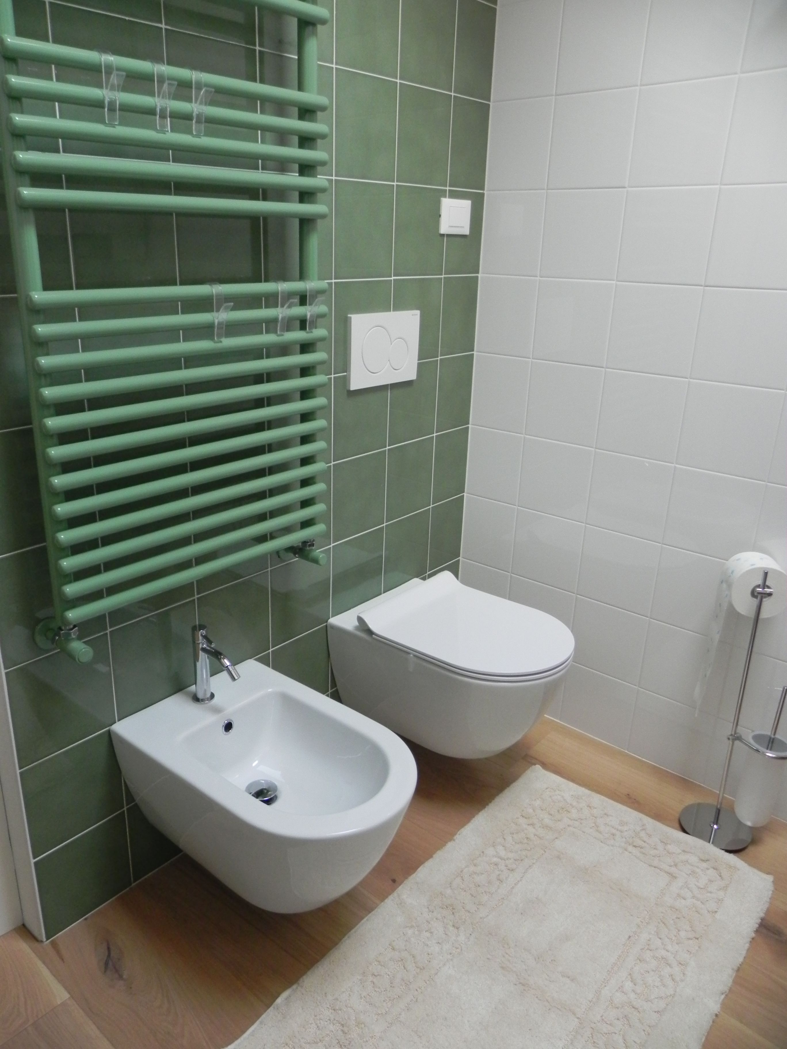Un bagno con bidet, water, porta asciugamani e porta carta igienica.