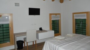 A bedroom with a bed, a desk, a chair, a television, and a window with a curtain. - da Meri Locazione Turistica Appartamento (Farra di Soligo)