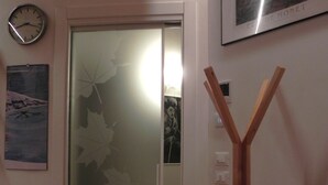 A room with a wooden floor, a sliding door with frosted glass, a framed picture on the wall, and a wooden easel. - da Meri Locazione Turistica Appartamento (Farra di Soligo)