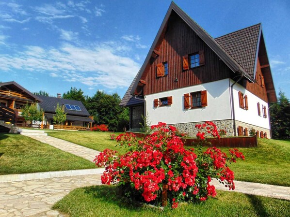A large, two-story house with a steeply pitched roof, wooden siding, and a stone foundation. - Guesthouse Lower Lakes (Plitvicka Jezera)
