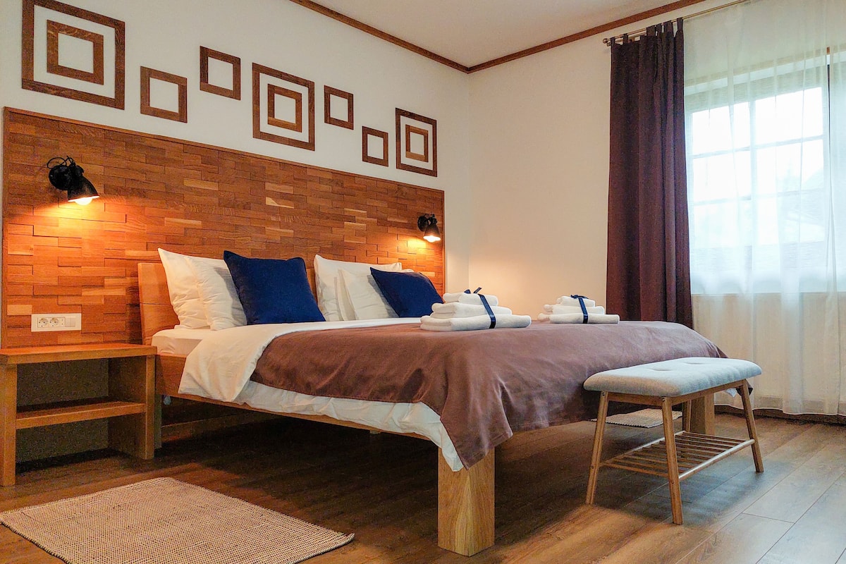 A neatly arranged bedroom with a wooden headboard, a bed with a brown bedspread, a bedside table, and a bench.