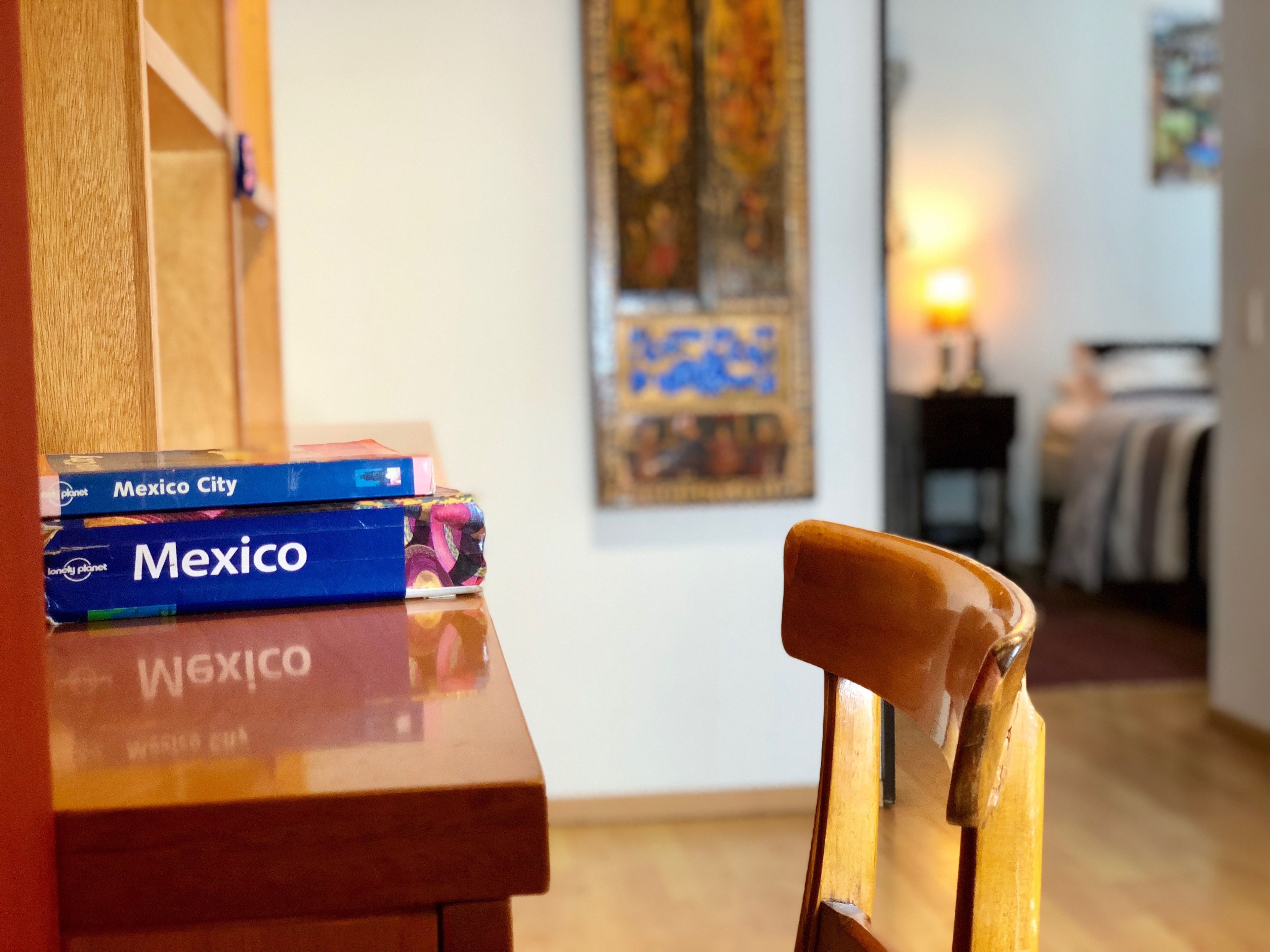 A wooden table with a stack of books titled 'Mexico City' and 'Mexico'. A wooden chair is in front of the table.