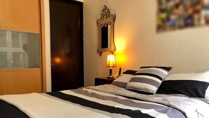 A hotel room with a bed, a nightstand with a lamp, a mirror, and a door. - Apartment Downtown 3 K (Mexico City)