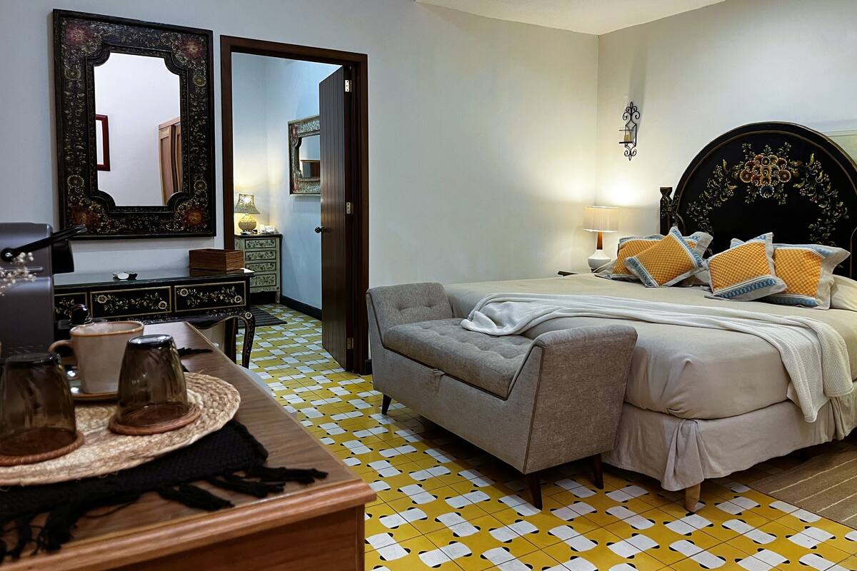 Ein Schlafzimmer mit einem Bett, einem Schminktisch, einem Spiegel und einem Couchtisch.